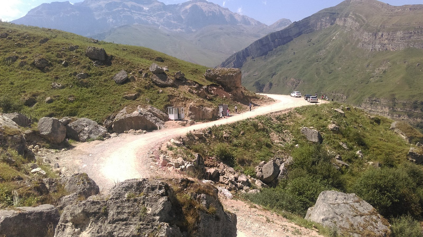 Qusar rayonunda Şahdağ Milli Parkına qalxan torpaq dağ yolu və arxada qayalı zirvələr