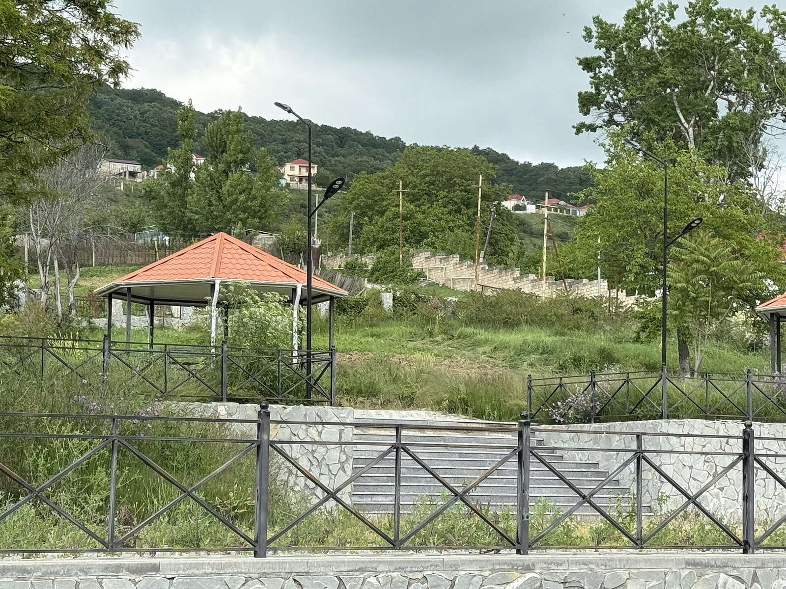 Meysəri kəndində abadlaşdırılmış park, çardaq və pilləkən, arxada meşəli təpə, Şamaxı rayonu